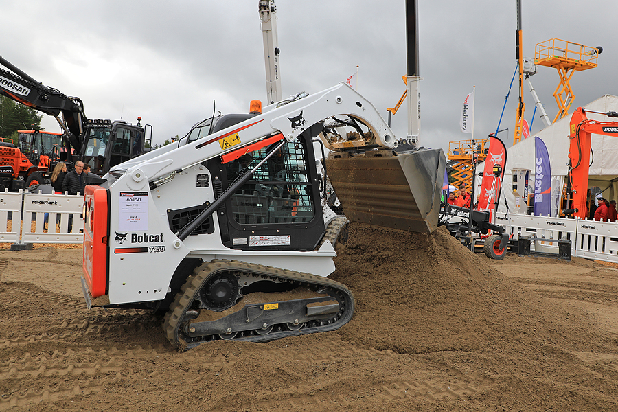 Operator works with Bobcat T450 Compact Track Loader on sand work site on Maxpo 2017.