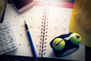 Notebook Calendar With Pen, Mobilephone, Calculator, Clock And Construction Hard Hat; scheduling ahead of time