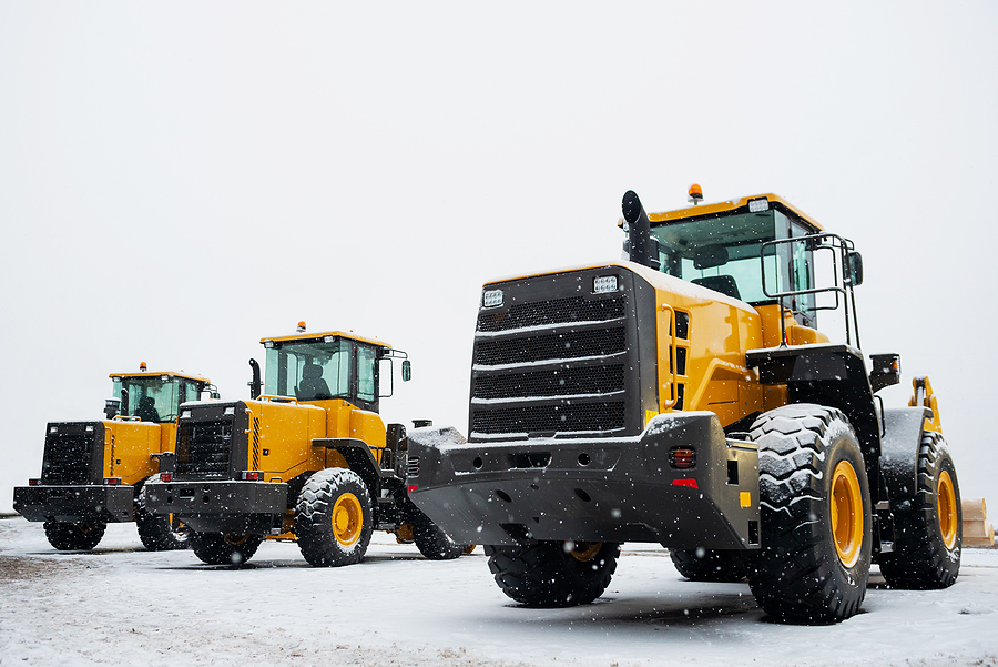 Yellow wheel front loaders. Construction and handling equipment. Heavy diesel tractor, construction machinery, industrial vehicle. Winter construction